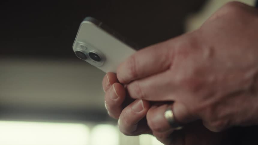 A middle aged man with a ring uses a smartphone