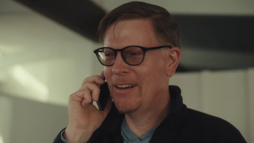 Man stands indoors while talking on a smartphone