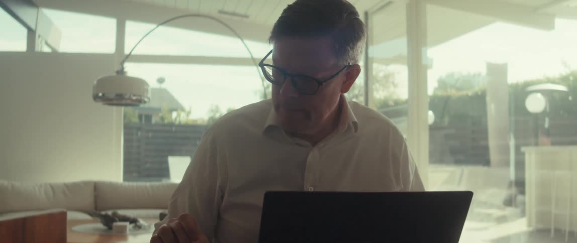 Man in glasses and a light shirt works concentratedly on a laptop