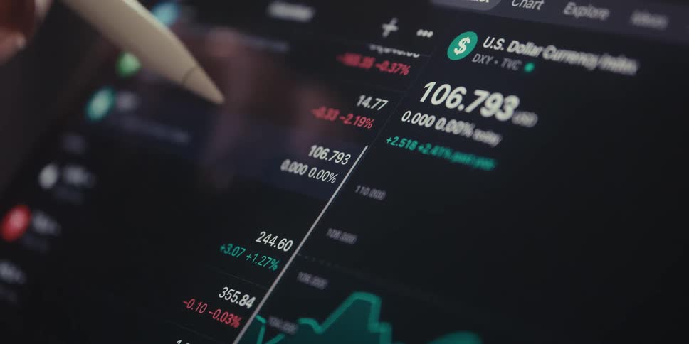 A digital pen hovers over a screen displaying financial data including the us dollar currency index suggesting analysis of exchange rates and market trends