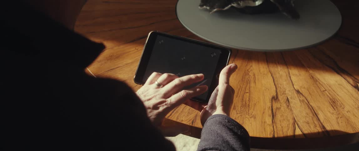 A person interacts with a tablet screen displaying tracking markers on a wooden table