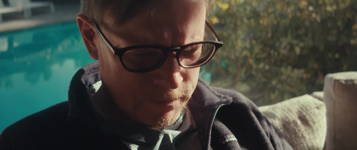 A man with glasses looks down