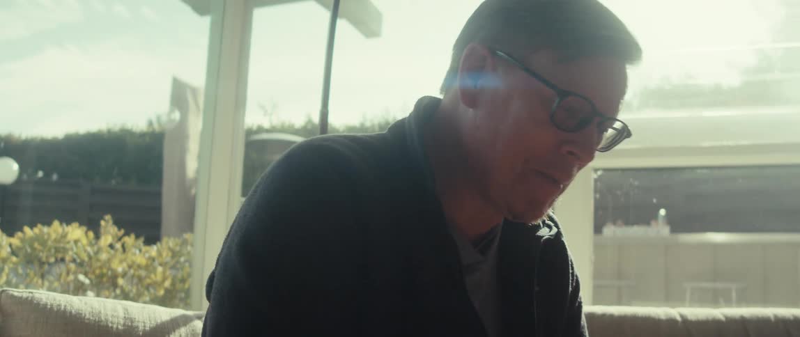 Man with glasses talking while sitting on a sofa