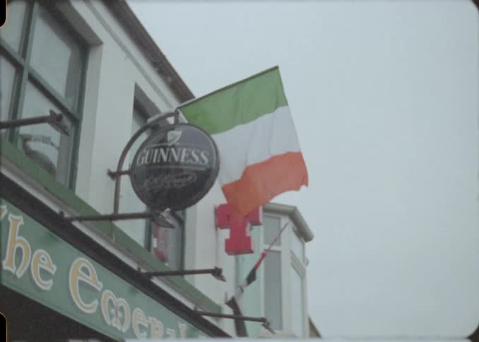 The irish flag flies next to a guinness sign on the front of a pub