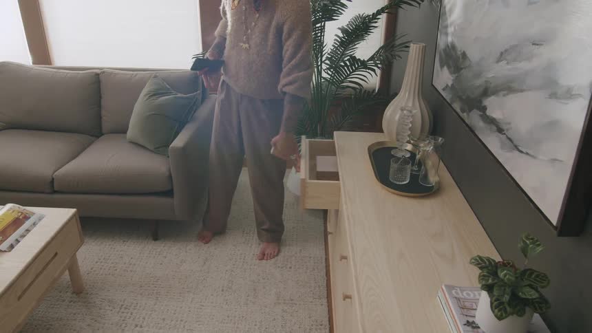 Person taking a small box from a drawer in a cabinet in the living room
