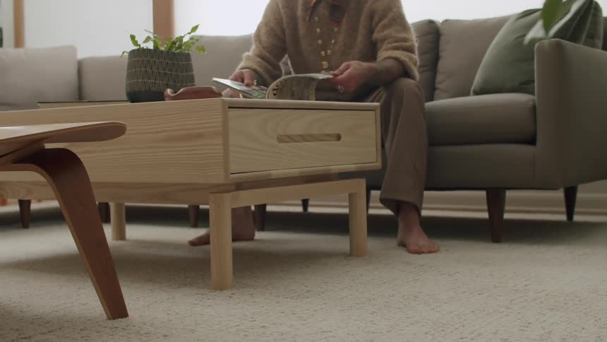 Person sitting on a sofa in the living room leafing through a magazine