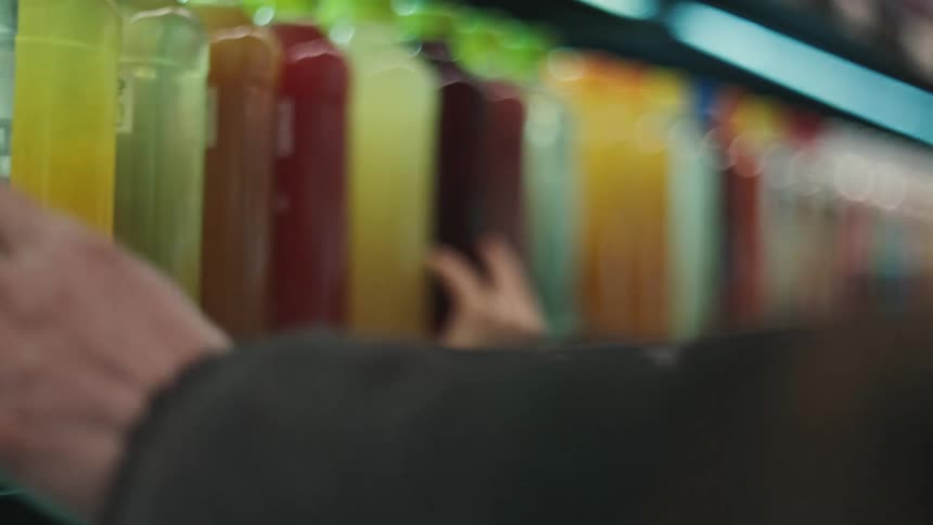 Mother and daughter checking fruit juice price tags while shopping at a grocery store
