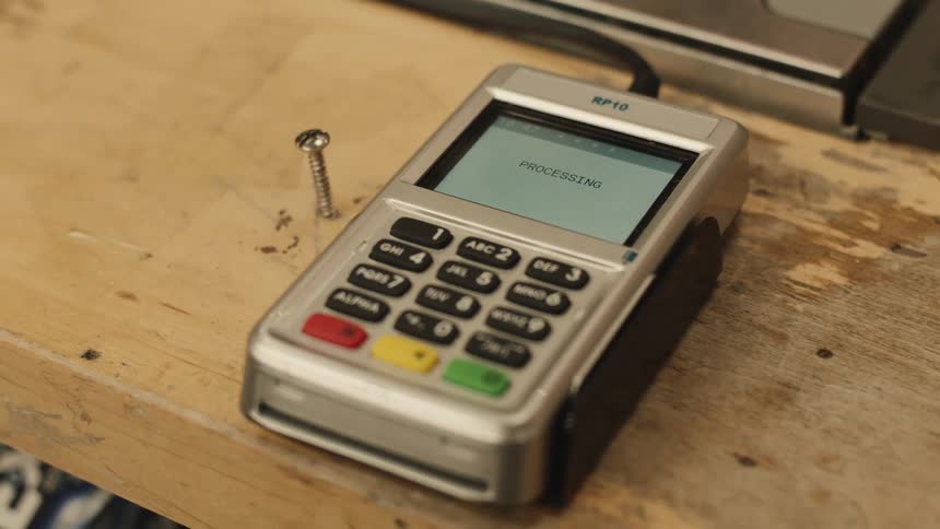 Someone taps a contactless card on a payment terminal which reads present card with a total of 14590 which changes its screen to processing to finally indicating that the purchase was approved