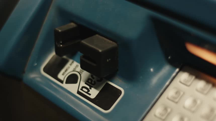 A persons hand with red nails typing on some buttons with numbers and then placing their card in a machine