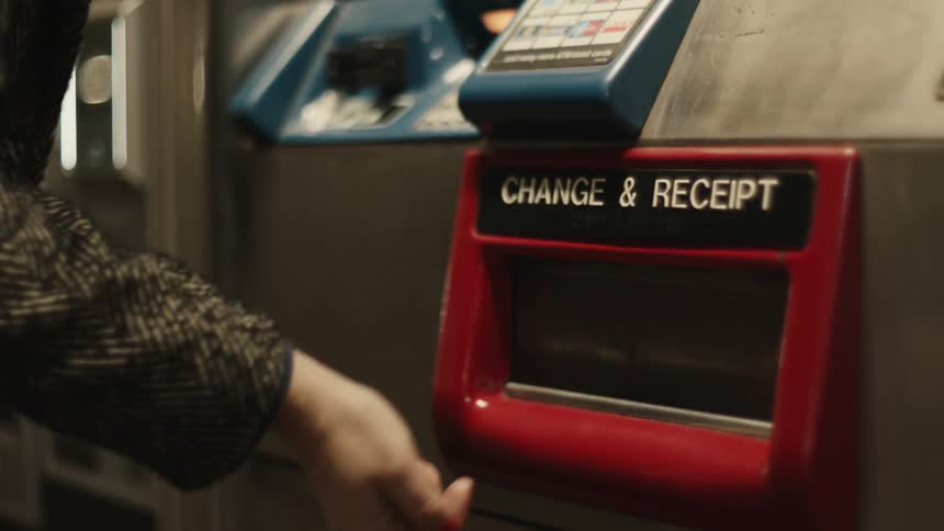 A womans hand with red nails and a coat taking change in coins from an atm