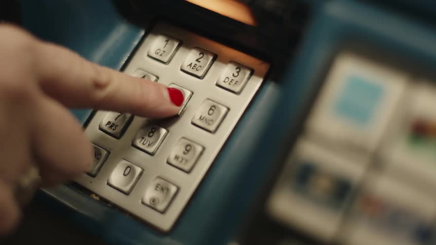 A womans finger with red nail polish presses the numbers on a blue atm keypad