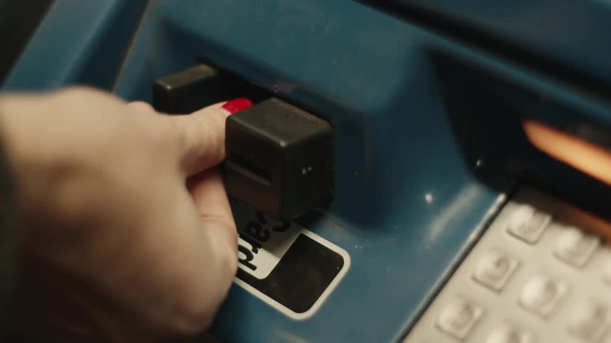 Close up of a womans hand putting a card into an atm