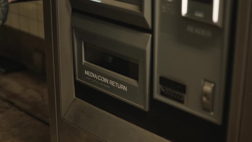 A person is retrieving coins from the lower slot of a vending machine