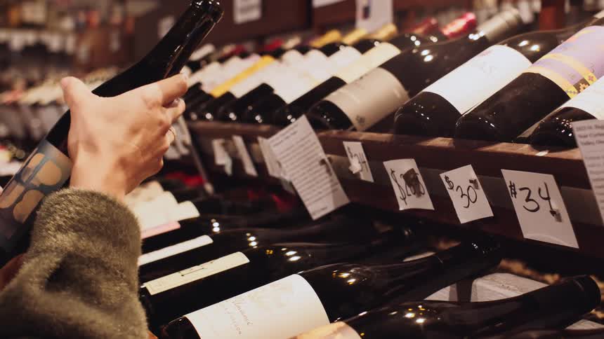 Pair of hands picking up a bottle of wine in a market