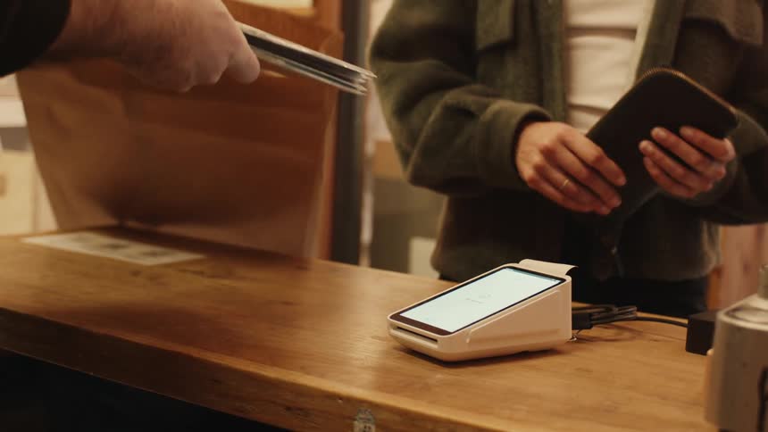 Person making payment at a machine and then picking up a bag with groceries