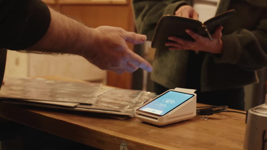 Hand setting up a payment machine on top of a wooden table