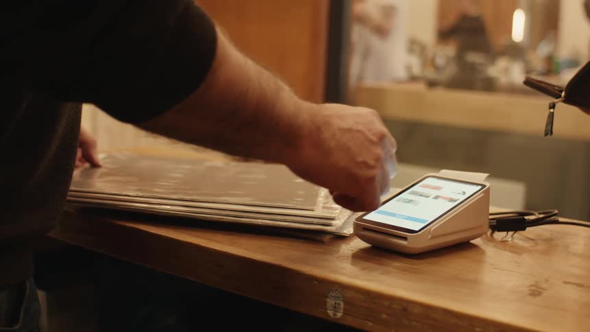 Fingers of a person setting up a payment machine in a store