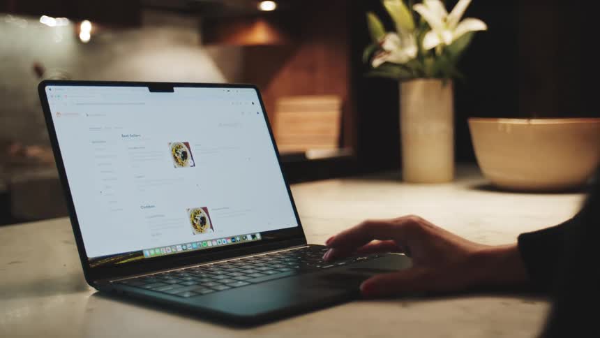 Hands of a person interacting with a laptop on top of a countertop