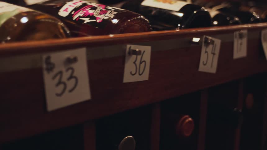 Wooden wine rack displaying wine bottles with price tags