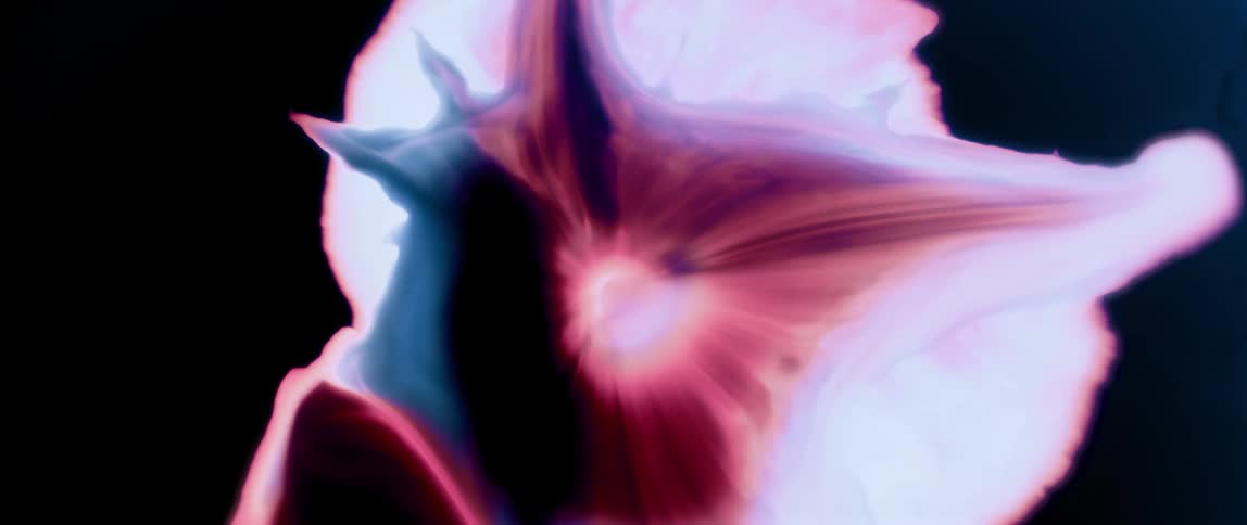 Predominantly pink and white abstract paint expanding against a black background
