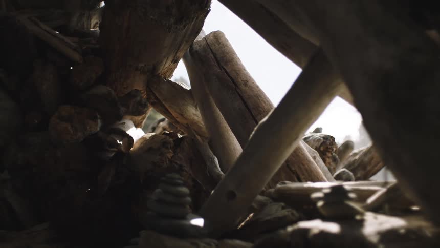 View of some large structures made from driftwood rocks and some stacked stones on a sunny day