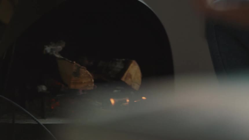 Hands putting firewood on a fire