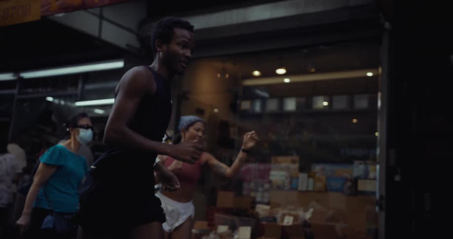Two people are jogging on a city street near a market area