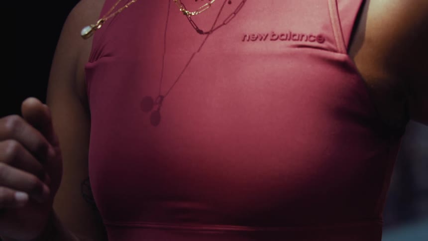 As woman runs the pearl necklace around her neck sways rhythmically against the maroon new balance tank top
