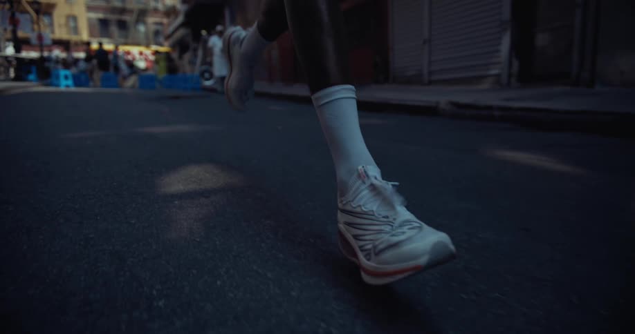 Feet with white sneakers running on the street
