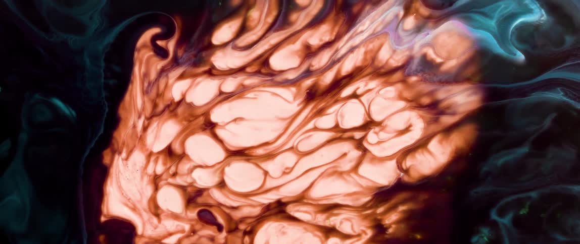Extreme close up of a predominantly red liquid bubbling in an abstract manner