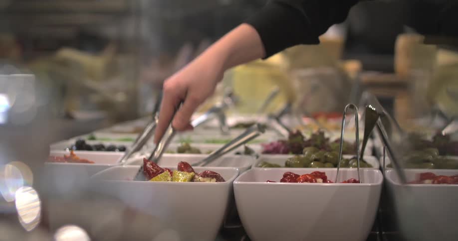 Hand arranging food from a buffet on small white plates