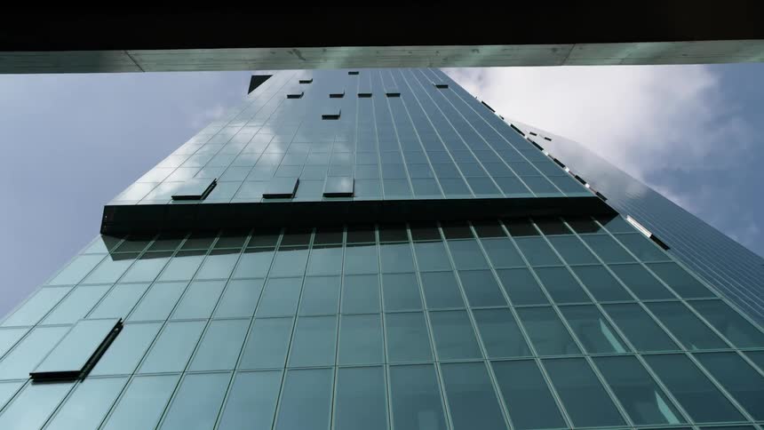 Tall skyscraper in a downtown city is revealed on a cloudy day