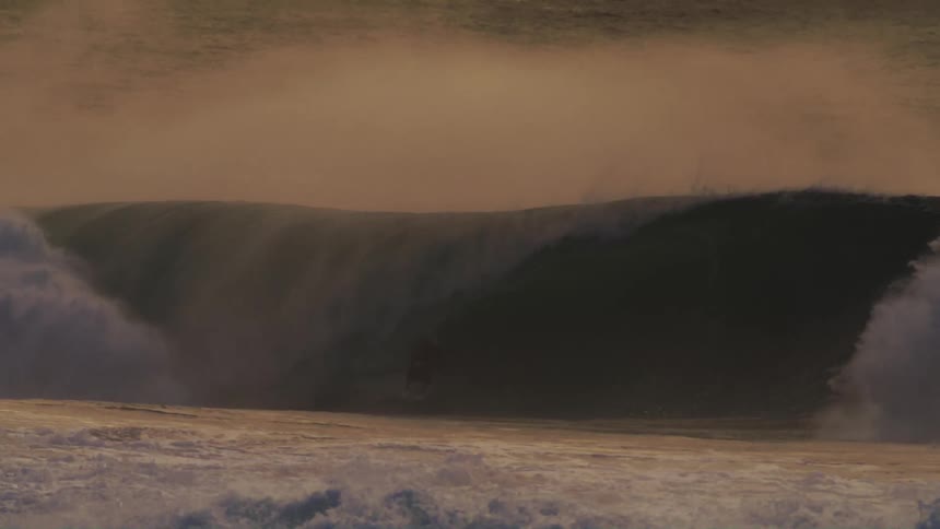Surfer riding a strong wave at dawn