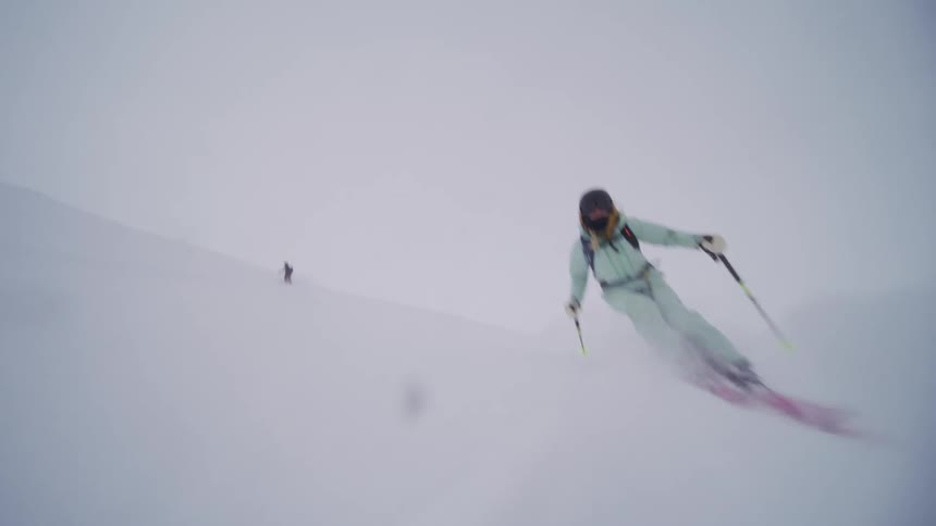Two people skiing down a mountain at high speed