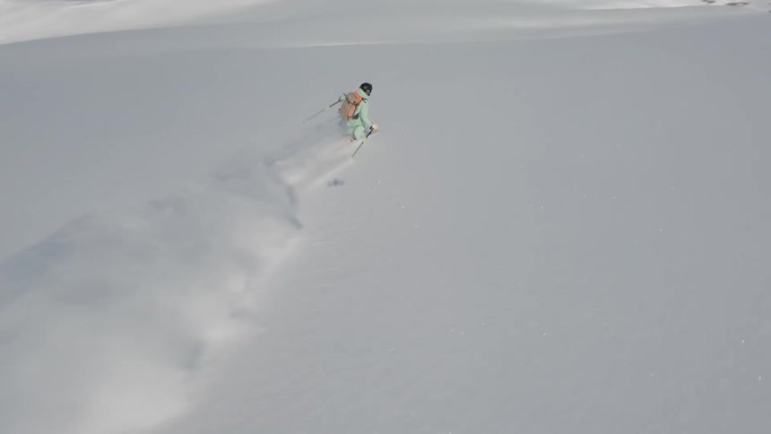 Skier kicks up a lot of snow while skiing down a mountain slope on a winter day