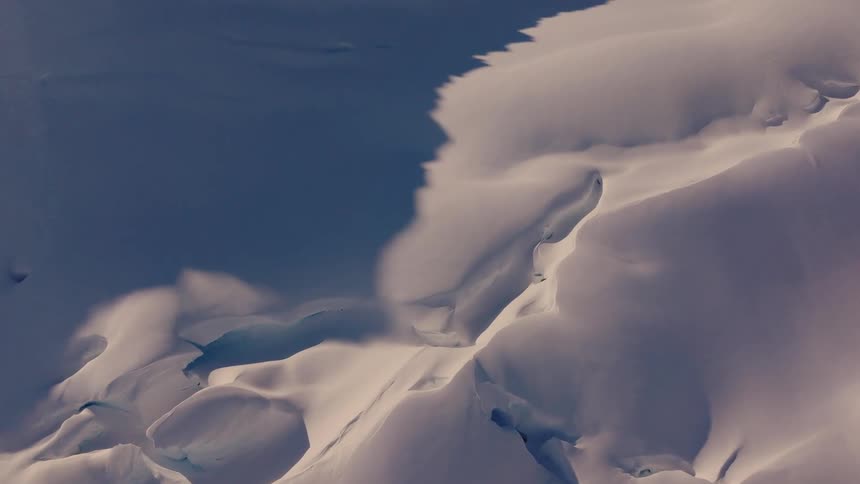 An abstract closeup view of a snowcovered landscape with deep crevices and shadows