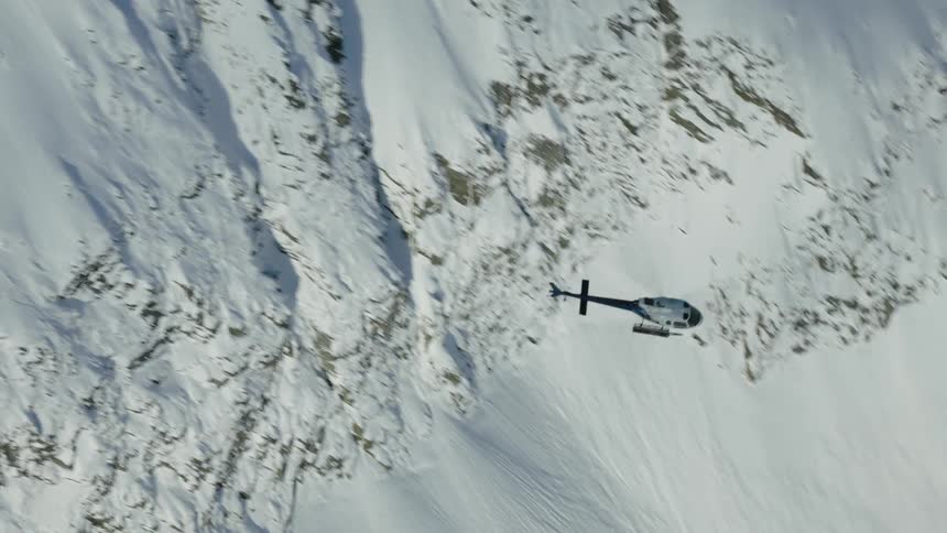 Aerial panorama of a helicopter flying above a snowy mountain