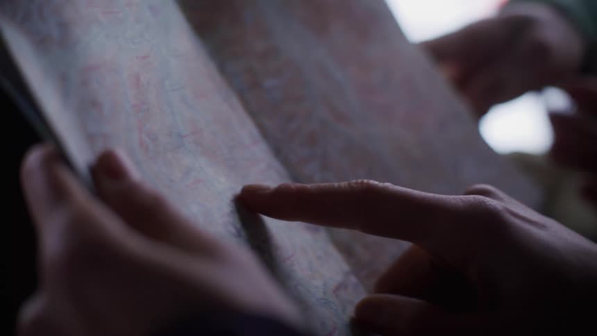 Two people try to find a place on a map during the daytime