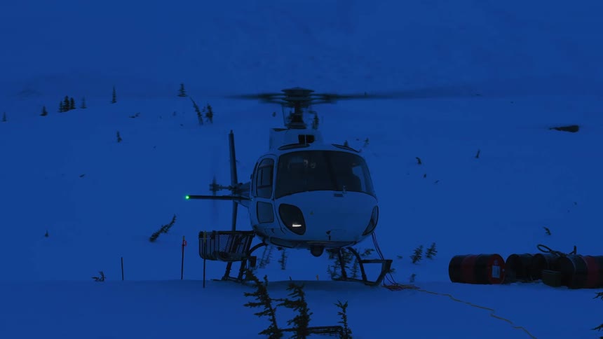 A helicopter is parked on a snowy terrain at dusk or dawn with its rotors spinning