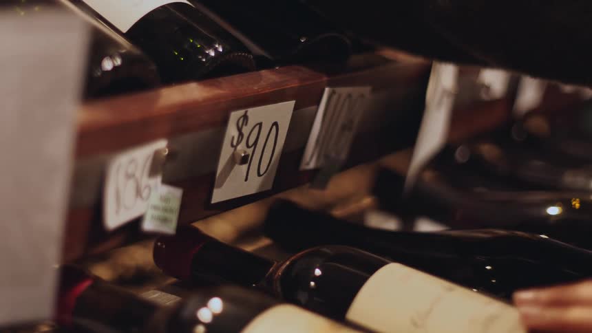 Hand picking up a bottle of wine in a store