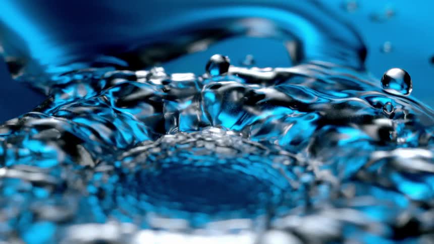 A drop of water splashes on the blue surface