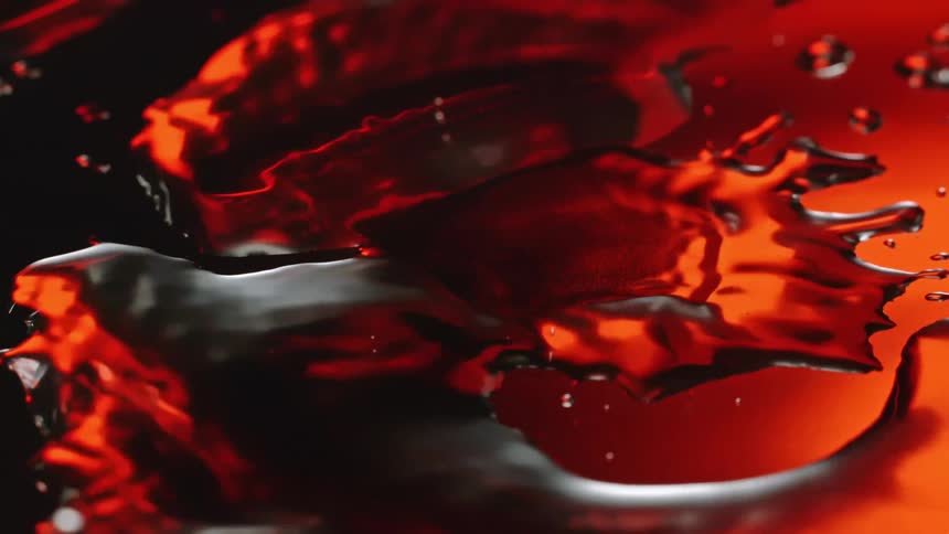 Water droplets falling on a surface with some small puddles and an orange reflection