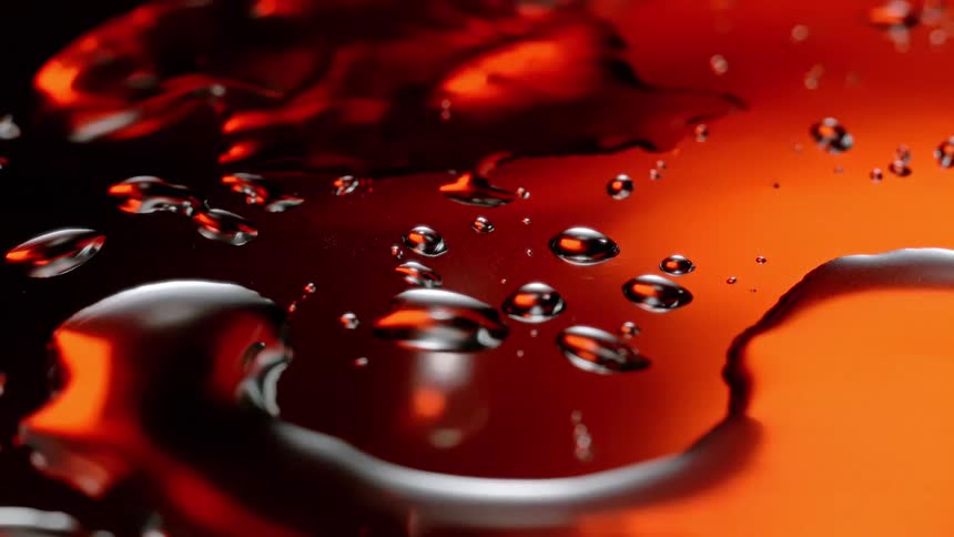 A few drops falling on a surface with an orange reflection
