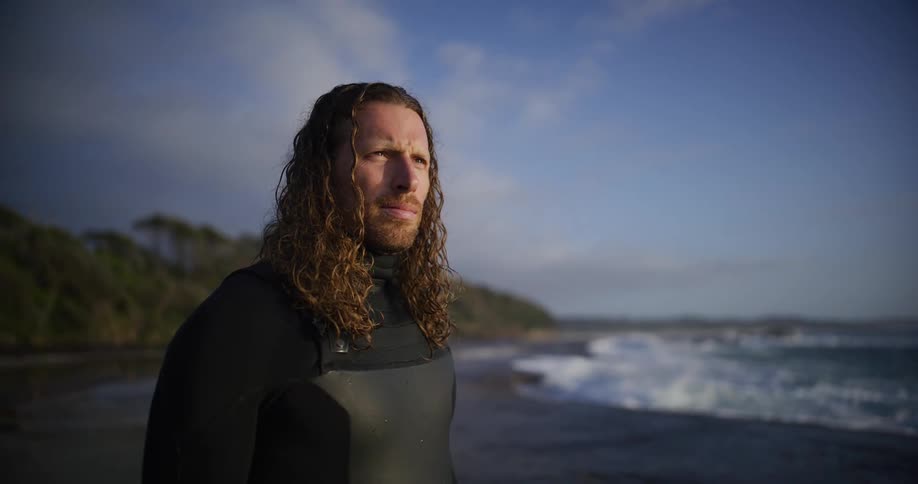 Silhouette of a curly haired man in swimming gear enjoying the sea view