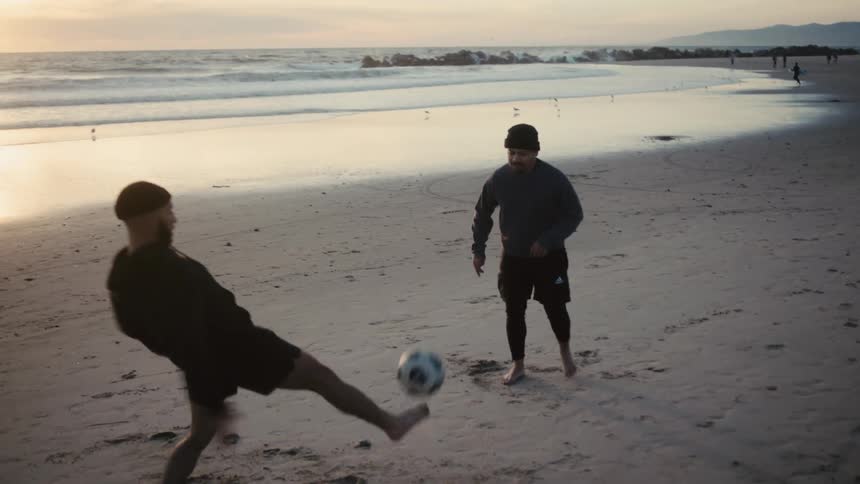 Men play with a soccer ball on the beach on an autumn day