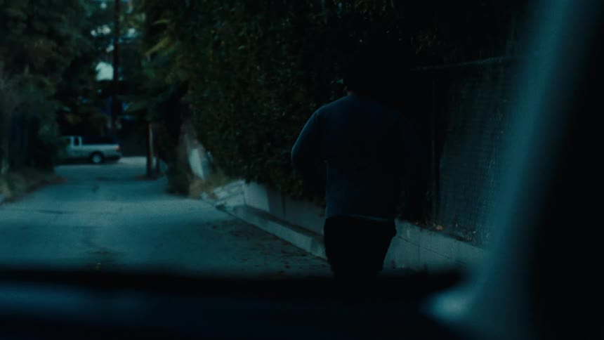 A person is running backwards on the street at night seen by a car