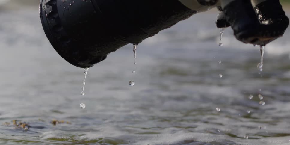 A large professional camera is slowly lifted out of the ocean water