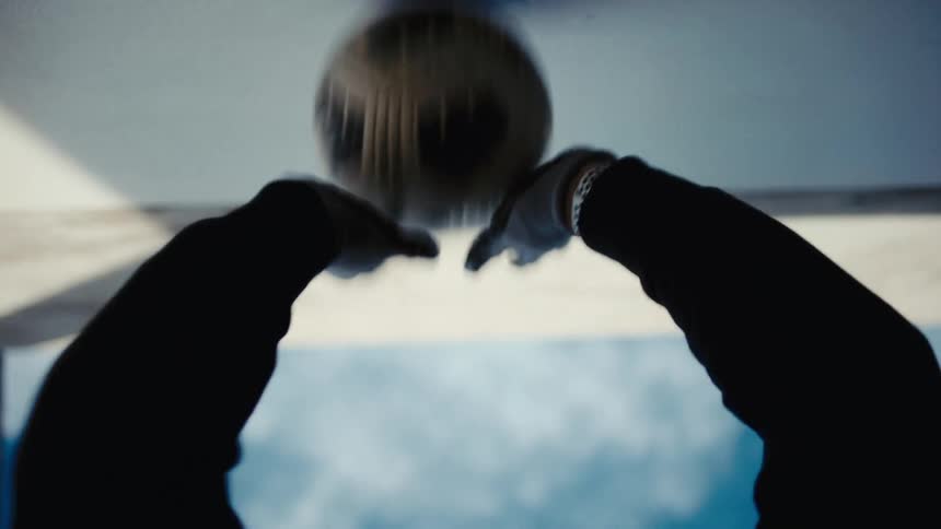 Pair of hands bouncing a ball against a wall