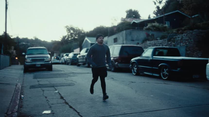 Man in a cap running outdoors through an urban neighborhood