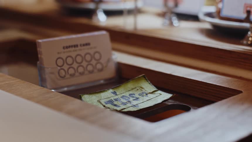 Customer puts cash in the slot for tips at a restaurant counter